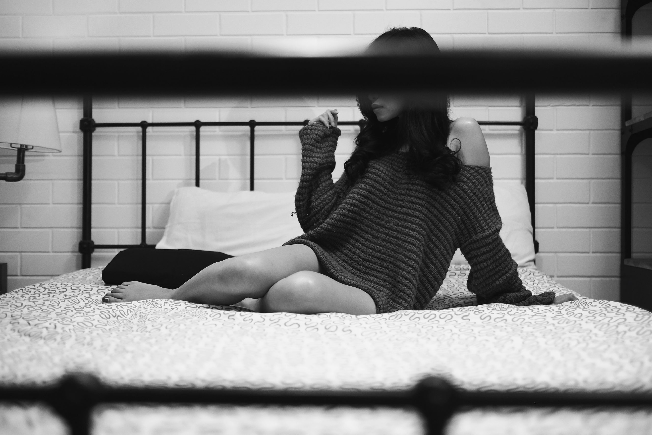 Kobieta siedząca na łóżku w domu – ilustracja do artykułu o ogłoszeniach towarzyskich w Szczecinie