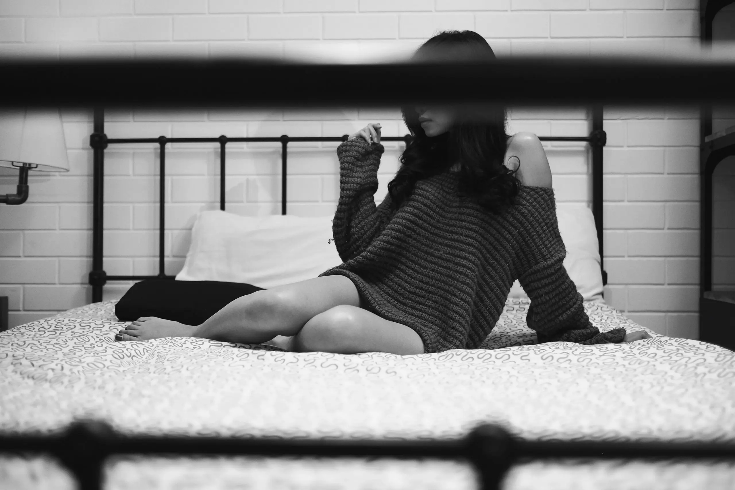 Kobieta siedząca na łóżku w domu – ilustracja do artykułu o ogłoszeniach towarzyskich w Szczecinie